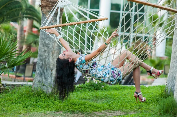 Chica balanceándose en una hamaca. Retrato de una hermosa joven feliz sonrisa vacaciones en hamaca. Desarrollando el pelo de mecerse. vacaciones concepto de vacaciones . — Foto de Stock