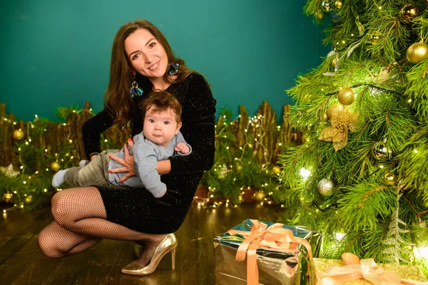 Happy mom with baby in new year setting. a young woman and a seven-year-old child look at the camera in a Christmas setting. family at Christmas. Happy Mom and son at the Christmas tree — Stock Photo, Image