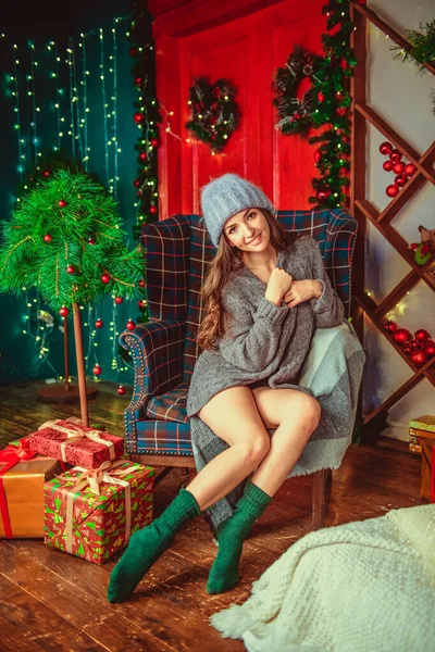 Fille dans un pull et un chapeau, sur un fond de Noël. Joyeux Noël et bonne année Adorable fille heureuse avec boule de neige tenir à la main. Portrait serré sur fond gris. Fille en santa chapeau et la sueur — Photo