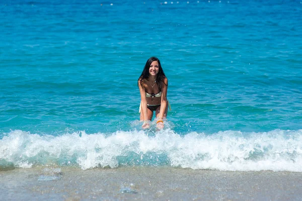 Όμορφο κορίτσι με τέλειο σώμα με μαγιό που παίζει με νερό στην παραλία των Μαλδίβων. Νεαρό λεπτό μοντέλο με μαυρισμένο δέρμα που διασκεδάζει στον ωκεανό. Σύννεφα και ουρανός στο βάθος. Χρώμα — Φωτογραφία Αρχείου