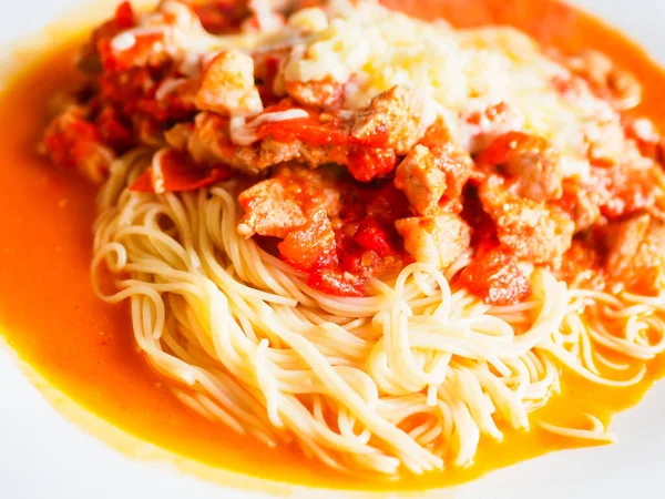 pasta with pieces of chicken and tomatoes on a white plate. Spaghetti with tomato sauce and pieces of chicken or turkey. Italian food. Selective focus