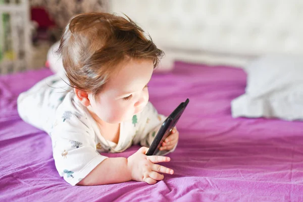 Ребенок учится по мобильному телефону. Маленький новорожденный ребенок тянется к мобильному телефону — стоковое фото