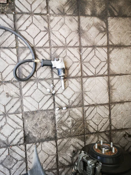Pneumatikus csavarkulcs egy hosszú tömlő feküdt a padlón kőburkolatok, felülnézet — Stock Fotó