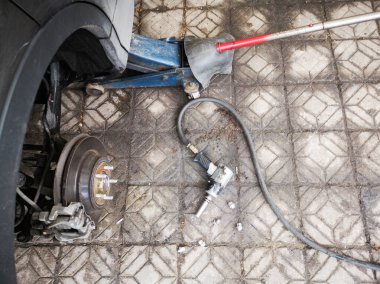 Araba lastiği fındık beton zemin bir yana araba jack Asansör ve otomobil lastiği düzeltmek için paslı metal bir parça ile Pnömatik anahtarı.