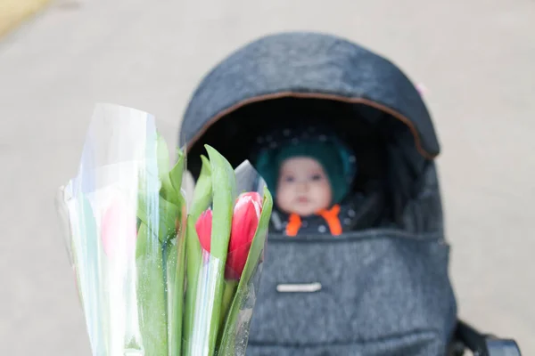 Flowers young mothers. Happy mother's day A small child congratulates moms and gives her flowers of red tulips. Thanksgiving for the child — ストック写真