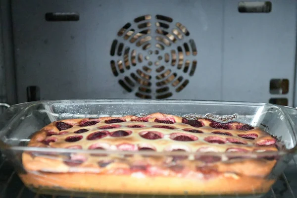 Jordbærtærte i ovnen. Tærte med marmelade og en dekorativ form på en bageplade. Tærte med dekorative figurer fra dej håndlavet. Rå hjemmelavet kage med hindbærsyltetøj. Tærte i ovnen på arket i - Stock-foto