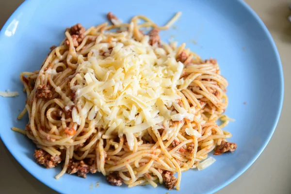 Cheese on pasta with meat, pasta on a blue plate