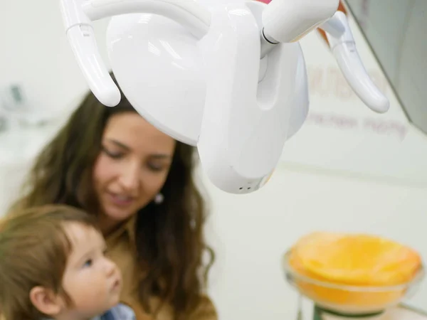 dental chair lighting device. back view. against the background of a mother with a child at a reception. Dental office lighting. Modern medical dental office lamp