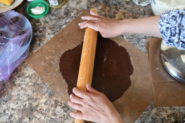 Mom rolls dough. chocolate dough. Hands working with dough preparation recipe bread. Female hands making dough for pizza. Woman's hands roll the dough. Mother rolls dough on the kitchen board with a r — Stock Photo, Image