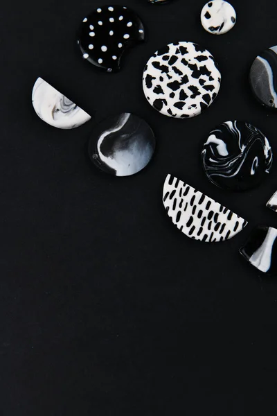 A product from polymer clay. Black and white polymer clay. Hand sculpting, product for earrings on a black background. View from above. Black and white jewelry earrings. Handmade polymer clay jewelry