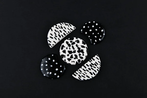 A product from polymer clay. Black and white polymer clay. Hand sculpting, product for earrings on a black background. View from above. Black and white jewelry earrings. Handmade polymer clay jewelry