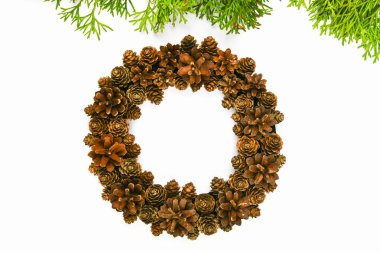 Beyaz arka planda el yapımı koni çelengi. Kenarına iğneler batırılmış. El işi. Noel için hazırlanıyorum. Yazmak için bir yer. Yukarıdan bak. Beyaz sırtlı köknar kozalaklı Noel çelengi