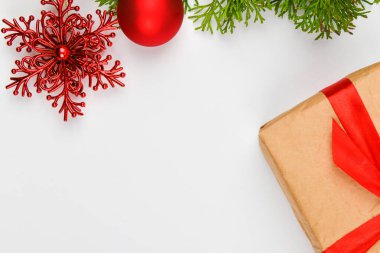 Beyaz arka planda kırmızı fiyonklu hediye paketi. Beyaz arka planda kozalaklı yeşil dallar. Yukarıdan bak. Yazmak için yer var. Noel arkaplanı