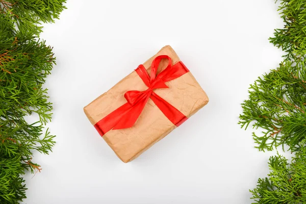 Envolvimento de presente com um arco vermelho em um fundo branco. Ramos verdes de coníferas em um fundo branco. Vista de cima. Lugar para escrever. Fundo de Natal — Fotografia de Stock