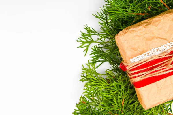 Empacotamento de presente feito de papel sobre um fundo branco. ramos verdes. lugar para escrever. Vista de cima. Ramos de árvore de Natal com e feito à mão presente de papel de embrulho Kraft, em branco — Fotografia de Stock