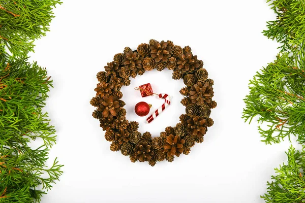 Grinalda feita à mão de cones em um fundo branco. decorado com agulhas para o lado. Trabalho manual. a preparar-se para o Natal. lugar para escrever. Vista de cima. Grinalda de Natal com cones de abeto em costas brancas — Fotografia de Stock