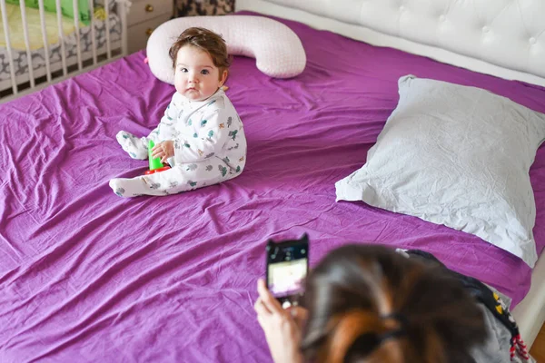 Mom photographs the baby on the phone. close on the phone. mom photographed her little son-girl using a device-oriented smartphone — Stock Photo, Image