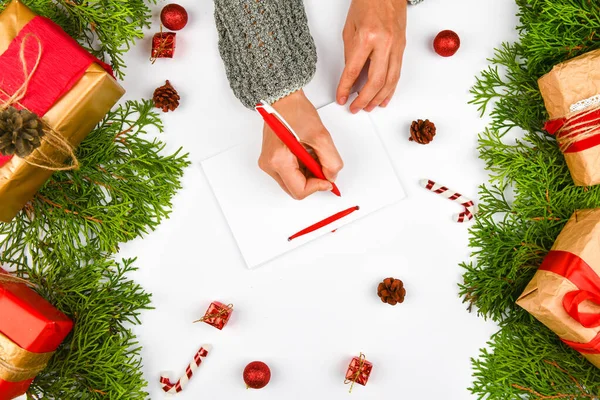 Dreams of goal plans make a list for writing a New Year\'s Christmas concept in a notebook. Woman hand on the background of fir branches New Year winter holiday Christmas flat lay. New Year Winter Holi