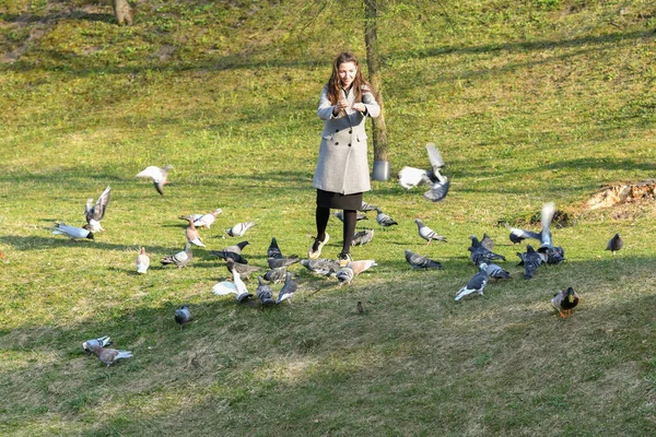 소녀들은 비둘기를 먹습니다. 햇빛 이 잘 드는 코호 다 공원에서. 동물을 돌보는 일. 아름다운 미소짓는 여자가 낮에 공원에서 비둘기에게 먹이를 주는 모습 — 스톡 사진
