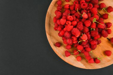 Siyah arka planda ahududu resmi. Tahta tepsi. Koyu taştan arka planda taze ahududu. Kapatın. Seçici odak. 