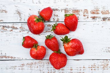 Beyaz ahşap arka planda olgun kırmızı çilekler..