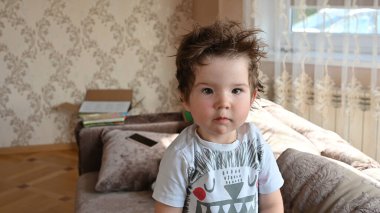 Üzgün kıvırcık çocuk kameraya bakıyor..