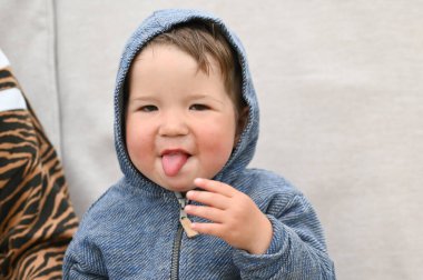 Küçük çocuk dil gösteriyor. Zevkle çocuğu oturttu. Yüksek kalite fotoğraf