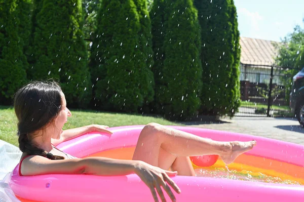 Menina espirra água na piscina — Fotografia de Stock