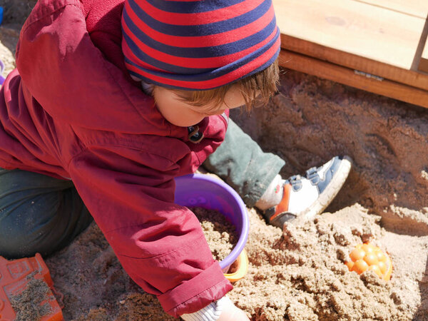 1-2 year old boy plays in the sandbox. High quality photo