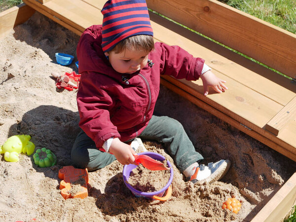 1-2 year old boy plays in the sandbox. High quality photo