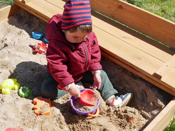 A child spends time playing in the sandbox. High quality photo