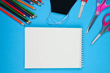 Mavi arka planda defter maskesi ve kalemler. Yüksek kalite fotoğraf