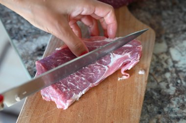 Bir kız büyük bir bıçakla bir parça et kesiyor. Yüksek kalite fotoğraf