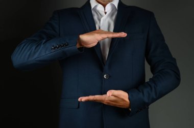 Takım elbiseli bir adam kollarını açar. Takım elbiseli bir adam siyah bir arka planda kollarını yana açıyor. Konsept: iş binası. Yüksek kalite fotoğraf