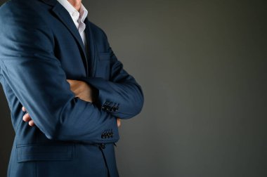 Takım elbiseli adam kollarını kavuşturdu. Siyah arka planda takım elbiseli bir adam. Konsept: İş hayatında inşaat