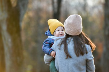 Çocuklu genç anne sonbahar parkında vakit geçiriyor. Yüksek kalite fotoğraf