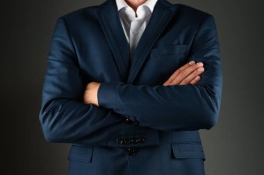 Takım elbiseli adam kollarını kavuşturdu. Siyah arka planda takım elbiseli bir adam. Konsept: İş hayatında inşaat