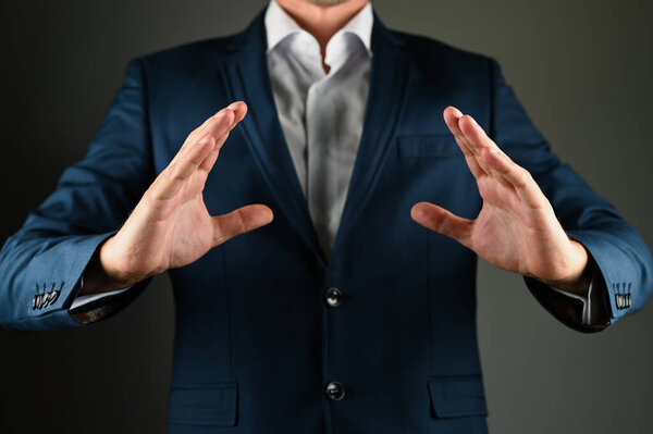 Мужчина в костюме расправляет руки. Человек в костюме расправляет руки в сторону на черном фоне. Концепция: строительство в бизнесе. Высокое качество фото