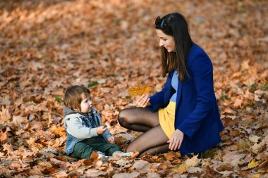 Çocuklu genç anne sonbahar parkında vakit geçiriyor. Yüksek kalite fotoğraf