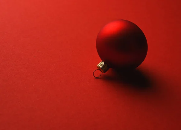 Bola de Natal vermelho encontra-se em uma superfície vermelha com sombras — Fotografia de Stock