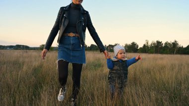 Anne ve çocuk gün batımında tarlada yürüyorlar. Yüksek kalite fotoğraf
