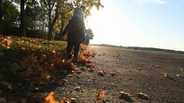 Sonbahar parkında koşan annesi olan bir çocuk.