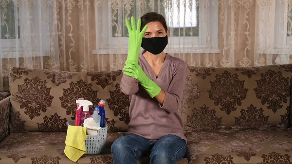 Dziewczyna w masce zakłada gumowe rękawiczki, żeby posprzątać pokój. — Zdjęcie stockowe