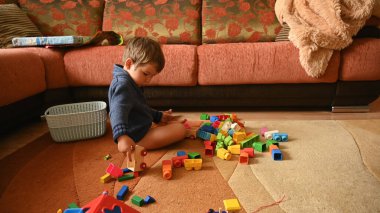 Çocuk halının üzerinde otururken oyuncaklarla oynuyor. Yüksek kalite fotoğraf