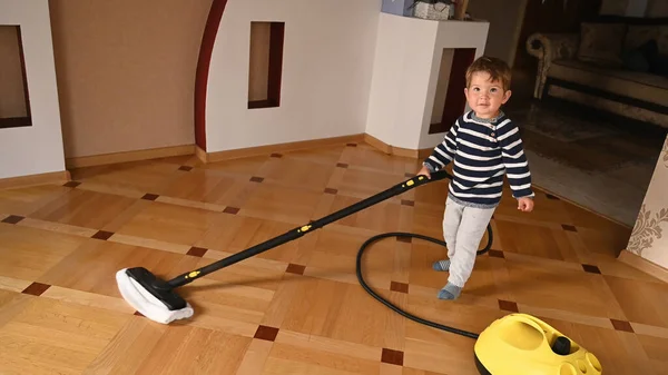 The child washes the floor with a steam cleaner. High quality photo