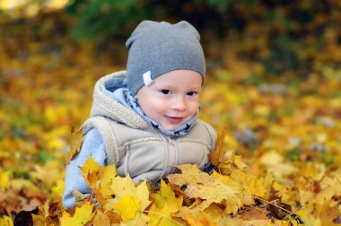 Düşen yapraklar üzerinde oturan iki yaşında erkek