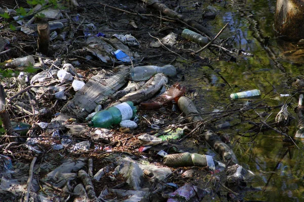 Zanieczyszczona rzeka z plastikową butelką i wieloma śmieciami — Zdjęcie stockowe
