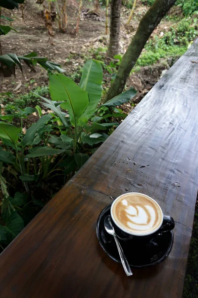 Filiżanka kawy z pięknym Latte Art na drewnianym stole bar — Zdjęcie stockowe