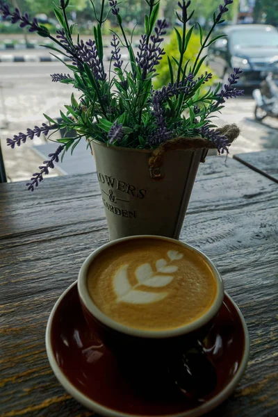 Filiżanka kawy z pięknym Latte Art i kwiat na drewnianym stole — Zdjęcie stockowe