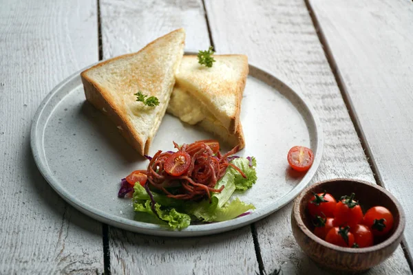 Beyaz ahşap masada beyaz bir tabakta tost sandviç ve sebze salatası Telifsiz Stok Fotoğraflar